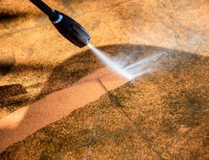 Defocused image. Cleaning backyard paving tiles pathway with high pressure washer. Spring clean up